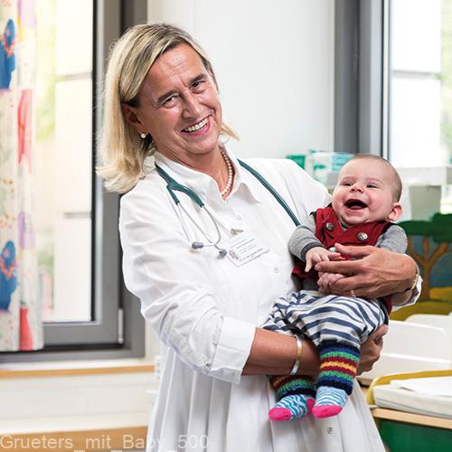 Annette Grüters-Kieslich bei ihrer Arbeit in der Kinderklinik: Sie hält herzlich lachend ein strahlendes Baby auf dem Arm.